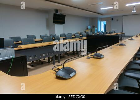A spacious modern corporate conference room featuring a long table, ergonomic chairs, and advanced technology for meetings and presentations. Stock Photo