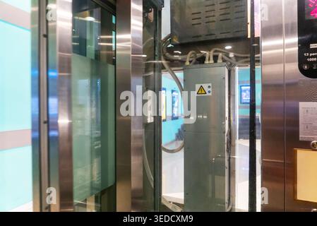 This image captures the interior of a modern elevator featuring transparent doors and a detailed control panel, showcasing innovative design and urban Stock Photo