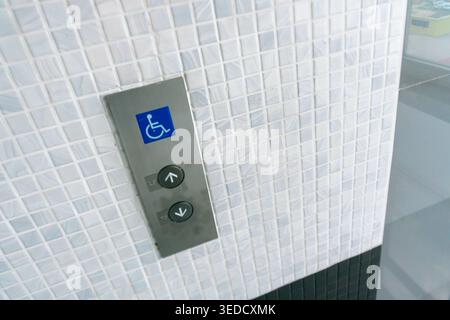 Close-up view of elevator buttons featuring an accessibility symbol, designed to assist individuals with mobility challenges in a modern building sett Stock Photo
