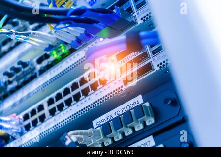 This image showcases a detailed view of network server equipment with colorful cables and blinking lights, highlighting modern technology and data com Stock Photo