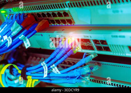 High-resolution image of a network switch with colorful ethernet cables connecting to it. LED indicators show active connections in a technological se Stock Photo