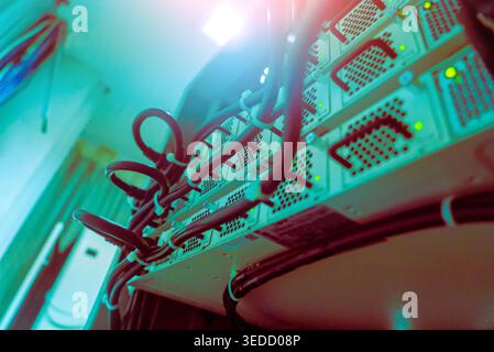 Captivating view of server equipment and cables in a modern data center. The image showcases intricately connected technology highlighted by blue ligh Stock Photo