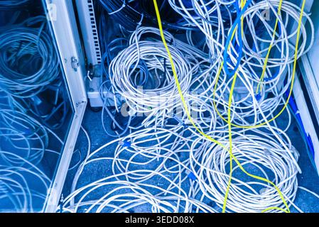 An intricate view of tangled cables and wires in a technology room. This image captures the chaos of connections, showcasing various colored wires sca Stock Photo