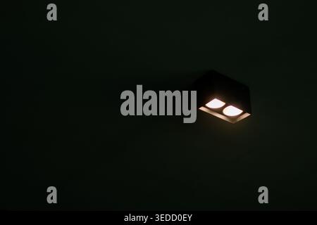 A stylish modern ceiling light fixture illuminating a dark room, creating a cozy ambiance. Perfect for interior design projects or lighting inspiratio Stock Photo