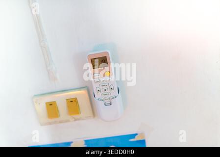 A modern remote control mounted on a wall beside light switches. This image illustrates home technology, comfort, and convenience in residential setti Stock Photo