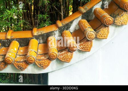 This image showcases a traditional Asian roof with intricate decorative tiles, surrounded by lush bamboo, highlighting the beauty of architectural des Stock Photo