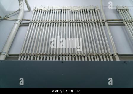 An organized array of pipes and tubes mounted on a wall, showcasing a modern industrial design. The clean lines and geometric arrangement highlight ef Stock Photo