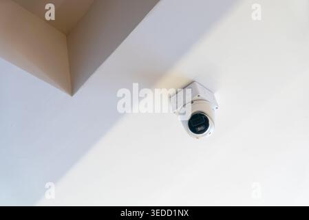 A modern security camera installed on the ceiling, designed for surveillance in indoor spaces. Ideal for enhancing safety and protection of property. Stock Photo