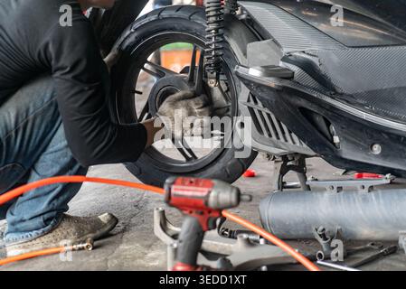 A mechanic working on a motorcycle tire in a garage, showcasing the meticulous process of repair and maintenance using specialized tools and equipment Stock Photo
