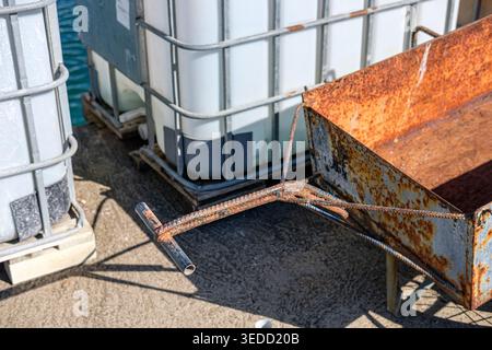 The contrast between old rusted metal and new white plastic storage containers Stock Photo