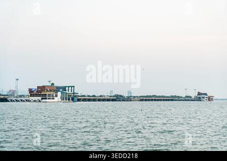A serene waterfront scene featuring a long pier extending into calm waters, surrounded by buildings and a peaceful horizon. Ideal for travel and leisu Stock Photo