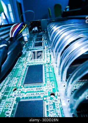 Close-up view of a green circuit board showcasing intricate microchips and wires, highlighting the complexity of electronic hardware and technology. Stock Photo