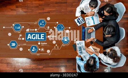 A diverse team engages in a collaborative meeting, analyzing agile methodology concepts using data charts and technology tools on a modern conference Stock Photo