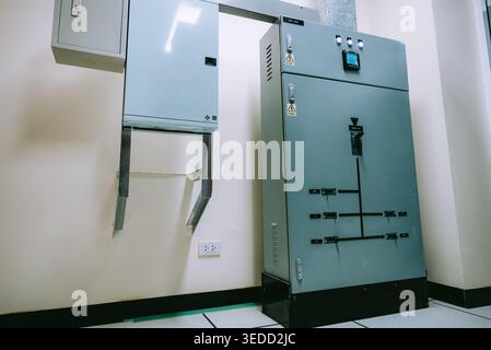 This image features a gray electrical control cabinet in an industrial setting, showcasing power management equipment and wiring essentials for safe o Stock Photo
