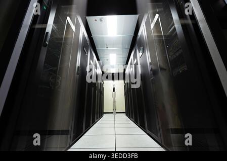 Explore a modern data center aisle filled with server racks. This environment showcases technology and infrastructure essential for data processing an Stock Photo