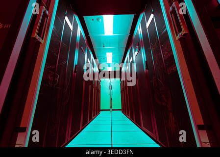 A captivating view of a modern data center featuring rows of servers illuminated by neon blue and green lighting, showcasing advanced technology and d Stock Photo