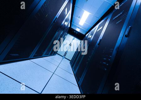 Explore a modern data center featuring rows of server racks in a sleek, organized environment. The image captures advanced technology and efficient de Stock Photo