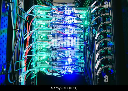 A view of a server rack in a modern data center showcasing colorful network cables and illuminated equipment, representing advanced technology and dig Stock Photo
