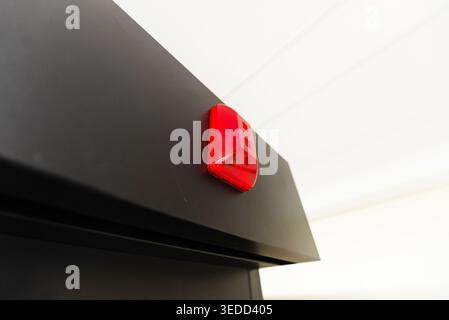 A close-up image of a red alarm light mounted on a black device, showcasing modern technology and safety features. Ideal for articles on security syst Stock Photo