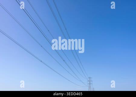A high voltage pylon with long cables against the blue sky Stock Photo