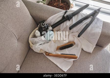 Hair styling tools and beauty products resting on a sofa with a white towel Stock Photo