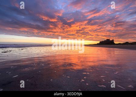Bamburgh Castle at sunrise with spectacular colours in the morning sky, Northumberland Coast, UK. Stock Photo