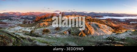 Panoramic view of frosty winter landscape with wooden stile over dry stone wall, Black Fell, Lake District, UK. Stock Photo