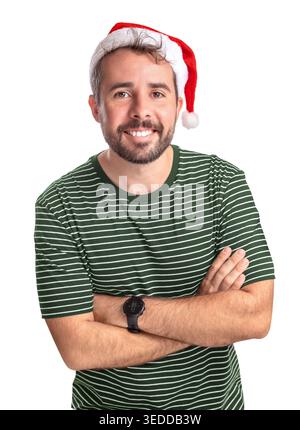 A man stands and smiles while wearing a Santa hat and a green shirt with stripes. He has a beard and crosses his arms in a happy pose. This scene is s Stock Photo