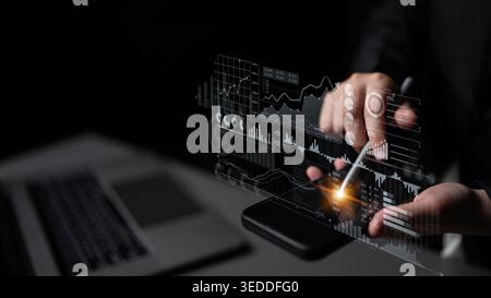 A close-up view of hands interacting with a digital tablet displaying finance data visualization, showcasing modern technology trends in a dark Stock Photo