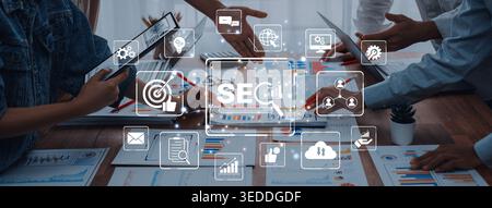 A diverse business team collaborates on digital marketing strategies, utilizing SEO tools and analytics in a modern office to boost online engagement Stock Photo