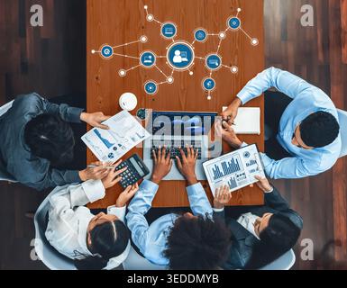 A diverse group of professionals collaborates in a modern office, analyzing data and charts around a laptop, showcasing teamwork and innovative ideas Stock Photo