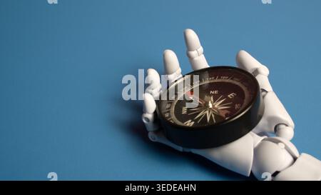 Close up of a white robotic hand resting on a black compass over a solid blue background symbolizing AI navigation and the future of exploration. Stock Photo