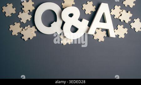 White wooden Q and A letters on gray background with scattered puzzle pieces for questions and answers concept Stock Photo