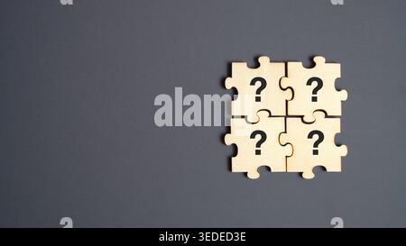 Four wooden puzzle pieces with black question marks printed on them on gray background for problem solving concept Stock Photo
