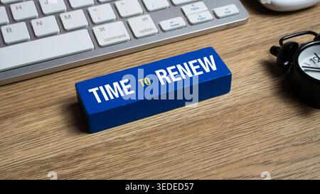 Time to Renew Message on Blue Block with Keyboard and Vintage Alarm Clock on Wooden Office Desk Stock Photo