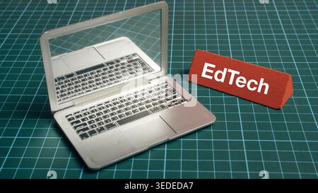 Miniature laptop with EdTech sign on green cutting mat representing digital education and remote learning technology Stock Photo