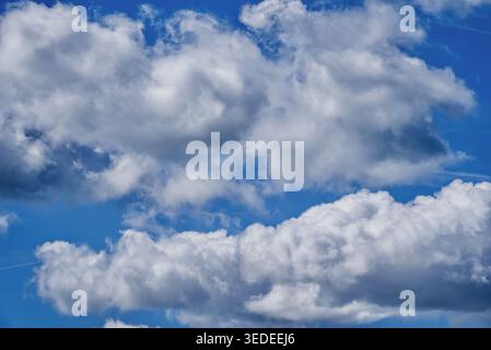 Picturesque cumulus clouds in a bright blue spring sky. Stock Photo