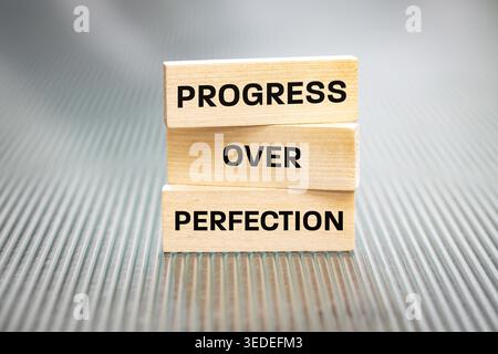 Progress over perfection. Sentence written on wooden tablets. Business concept. Motivating, supporting development. Close up. copy space Stock Photo