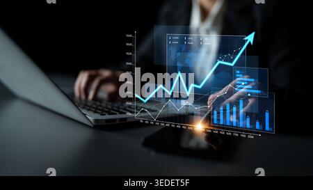 A business professional works on a laptop, analyzing financial data with interactive graphs and charts. The image illustrates modern technology in a Stock Photo