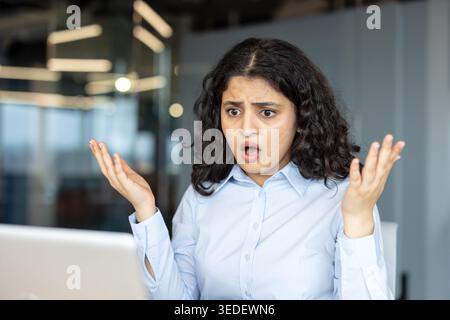 Indian professional woman at her laptop reacting with shock and frustration to a sudden system error while working remotely or in a modern office, hand to face, concerned expression Stock Photo