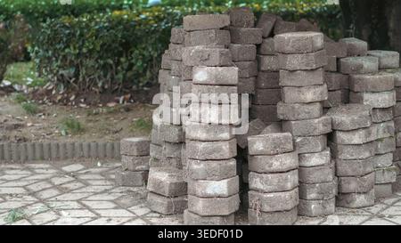 several stacks of weathered, octagonal paving stones covered in soil and dried grass Stock Photo