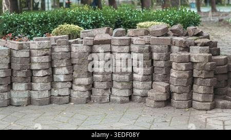 several stacks of weathered, octagonal paving stones covered in soil and dried grass Stock Photo