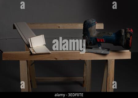 Woodworking setup with cordless jigsaw, wooden plank and materials arranged on workbench, concept for carpentry, DIY projects, preparation, constructi Stock Photo