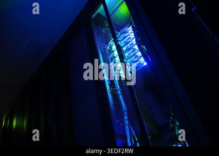 A dramatic view of a server rack illuminated by blue light. This image captures the essence of modern technology and infrastructure in a data center. Stock Photo