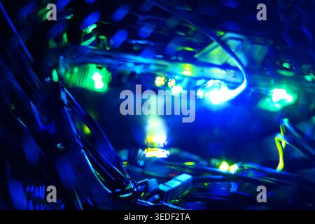 Discover the captivating interplay of bright blue lights amidst dark cables, showcasing a dynamic representation of technology and electronic networks Stock Photo