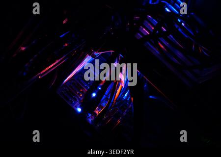 Close-up view of glowing cables in a dark server room, showcasing vibrant blue and purple lights. The image embodies technology and innovation in a mo Stock Photo