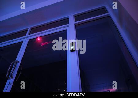 A modern office door featuring sleek glass design and ambient lighting creates an intriguing atmosphere in an urban workspace environment. Stock Photo