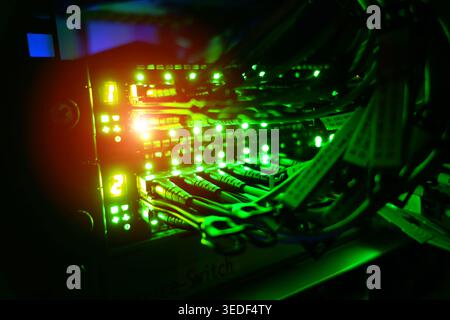 Close-up of an illuminated server switch showcasing vibrant neon lights and cables, emphasizing technology and network connectivity in a data center e Stock Photo