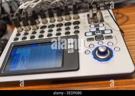 Close-up view of an audio mixing console showcasing knobs, faders, and digital display. Ideal for music production and recording-related projects. Stock Photo