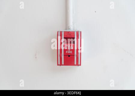 A red fire alarm pull station mounted on a white wall. This essential safety device provides a clear warning signal in case of emergency, promoting vi Stock Photo